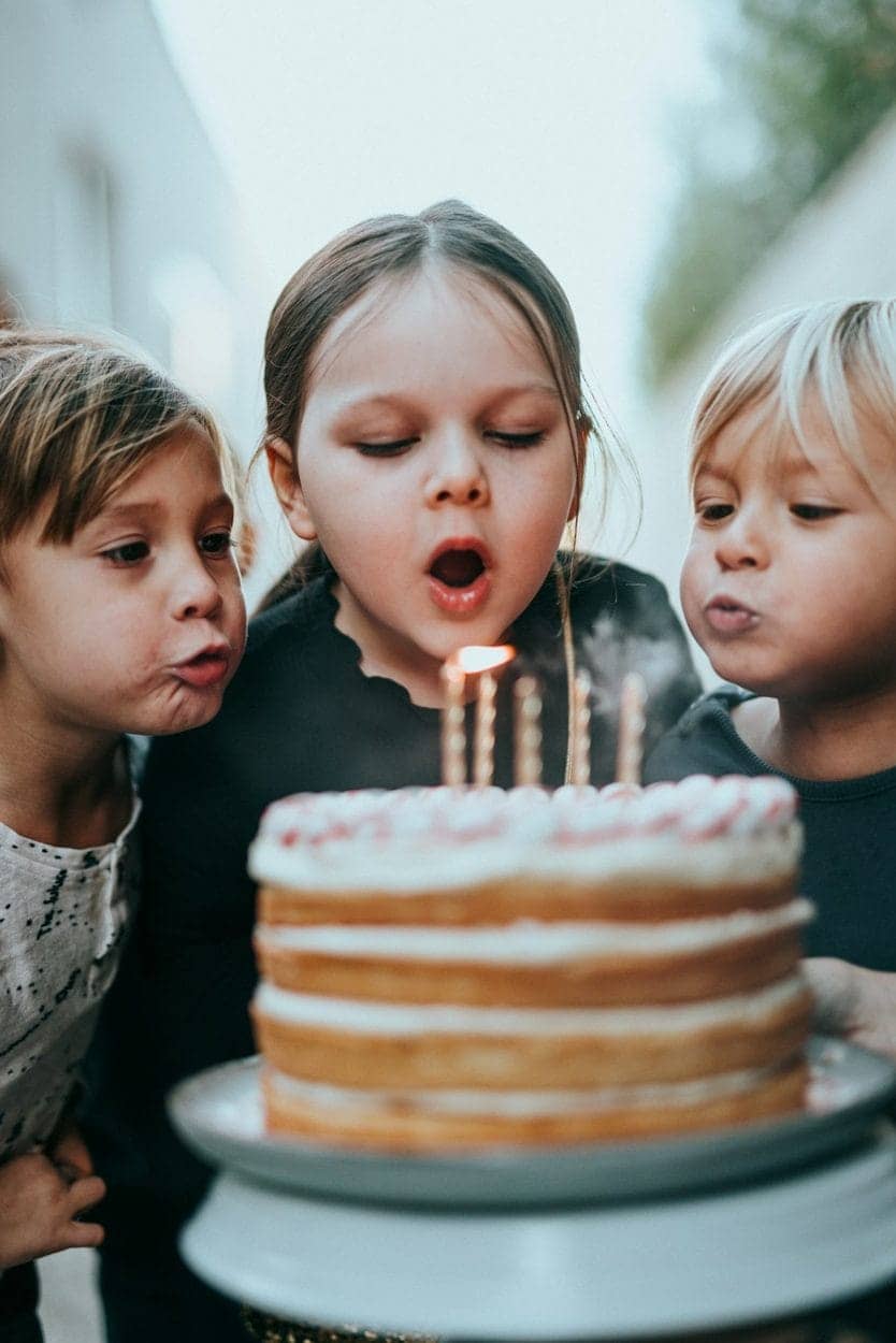 Crianças sorrindo enquanto apagam as velinhas de um bolo de aniversário
